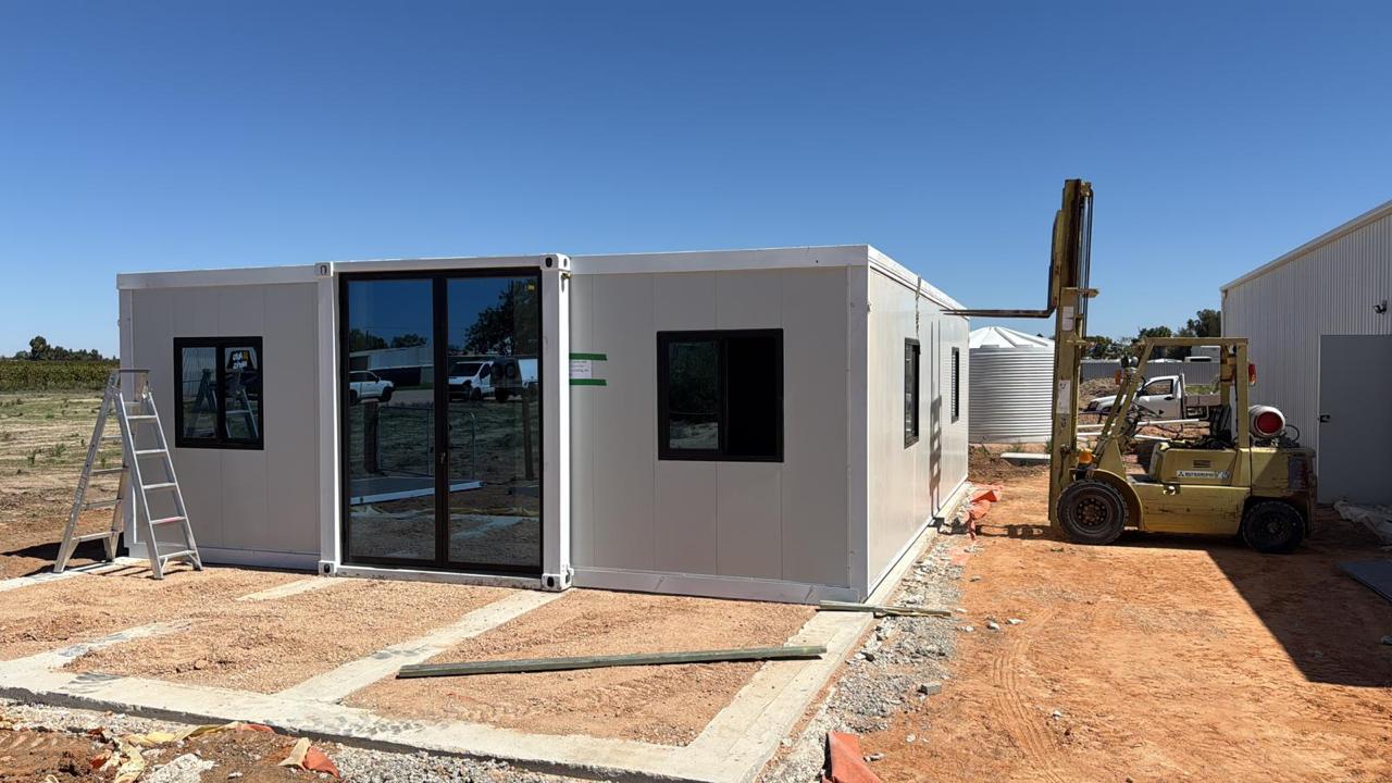 FlexiHomes expandable container home being assembled on site with forklift on red Australian soil